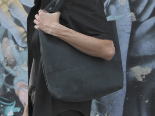 Close view of the Imminent Occurrence charcoal leather tote carried on the shoulder
