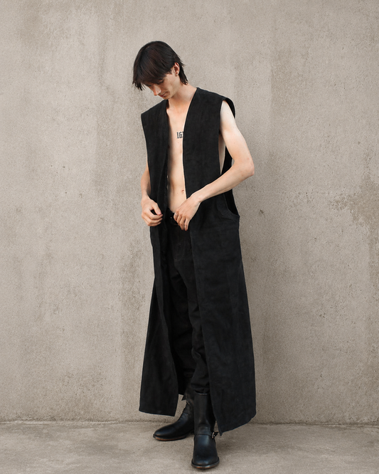Tim wearing the Imminent Occurrence Sleeveless Duster against a warm cement background