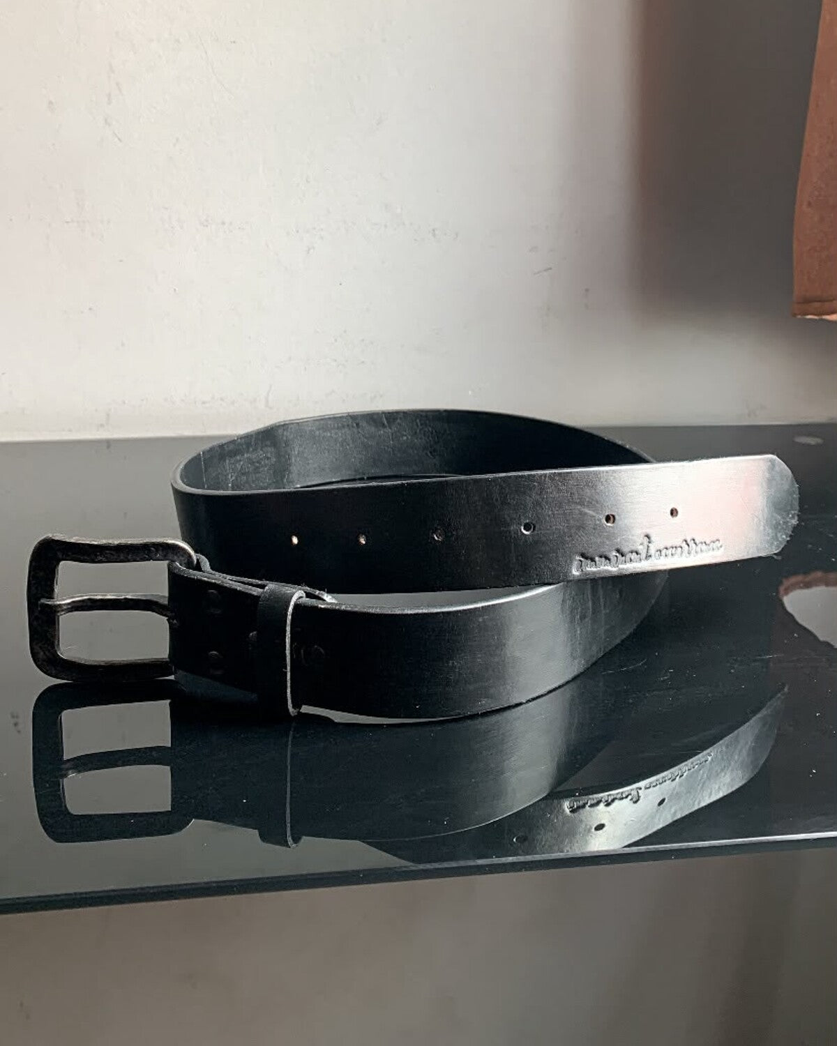 Aevum black leather belt showing buckle and hot-branded tip