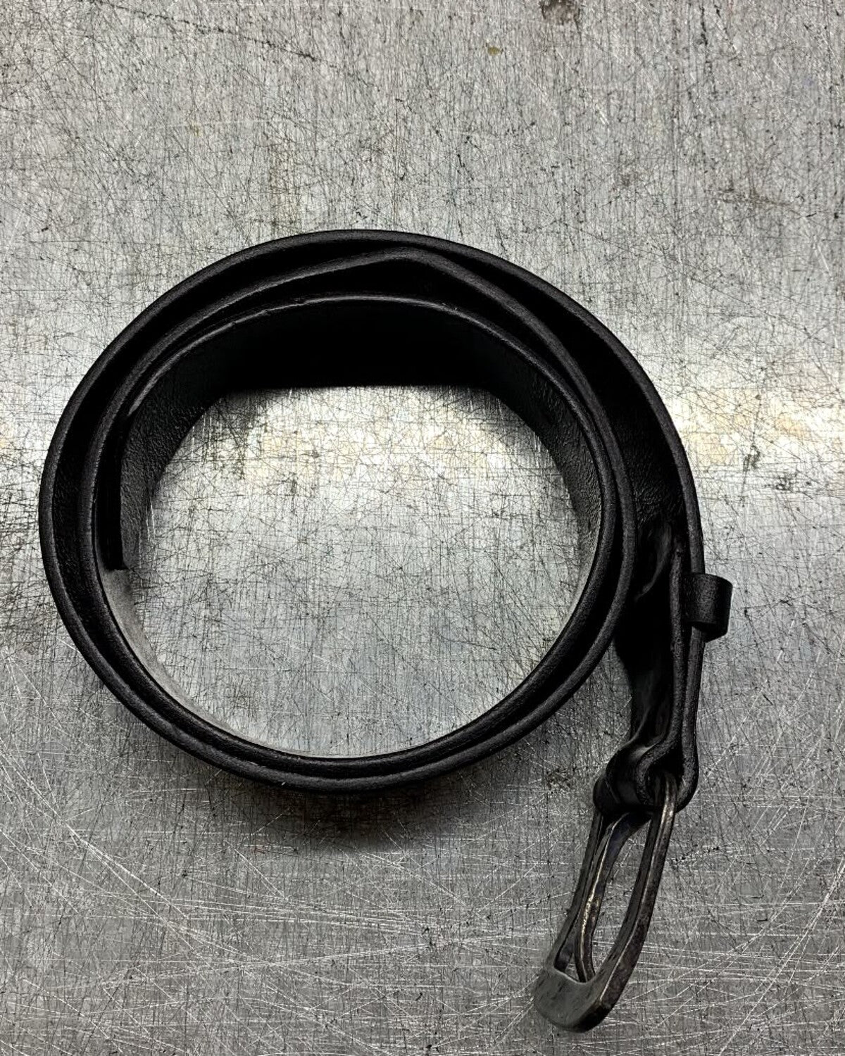 Aevum black leather belt coiled and viewed from above