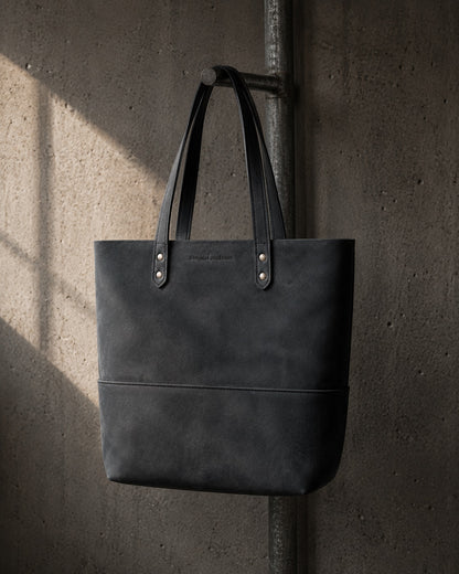 Imminent Occurrence leather tote bag hanging on industrial pipe
