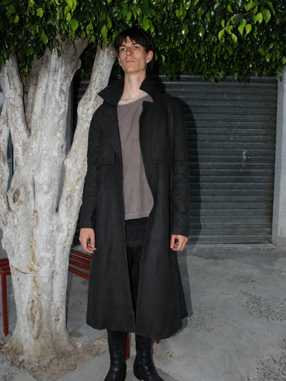 Model wearing the Imminent Occurrence handmade leather trench coat beneath a tree